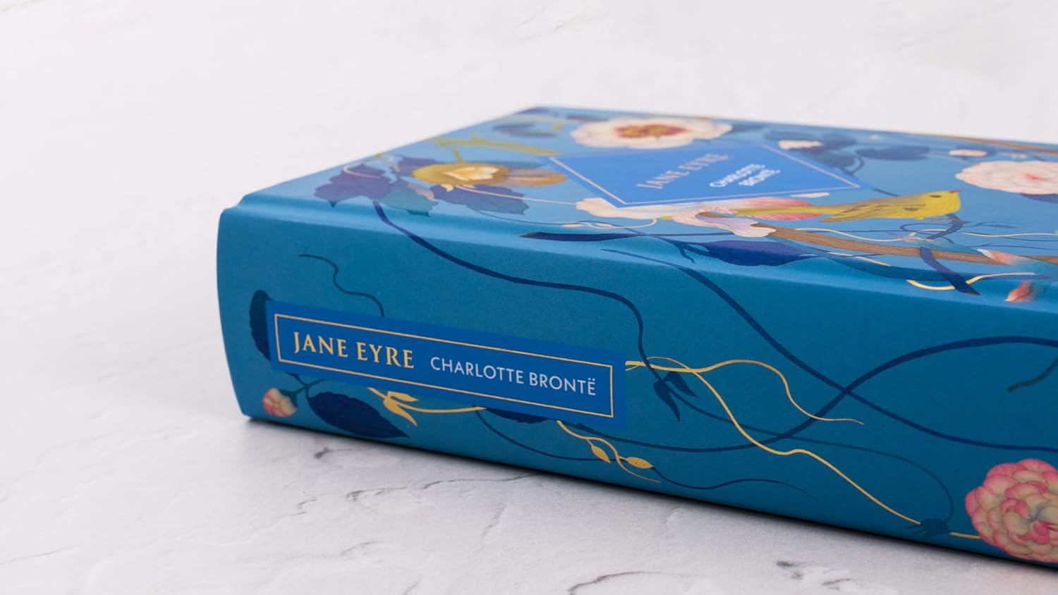 Blue book with 'Jane Eyre' by Charlotte Bronte on a white marble surface