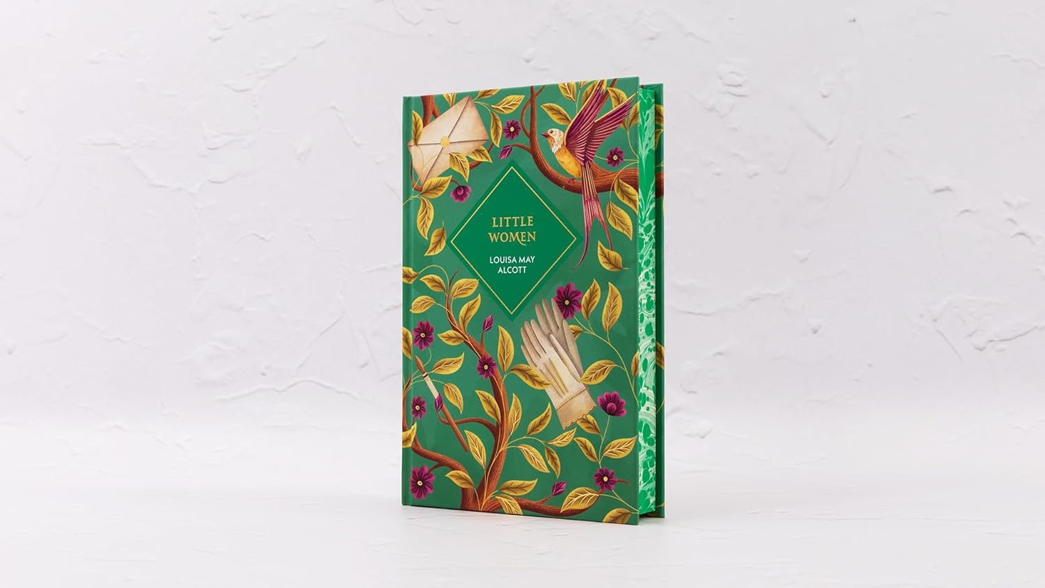 Decorative book with a green cover featuring floral and bird designs on a white background