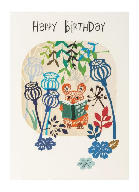 Birthday card with a fox reading a book among flowers and plants.